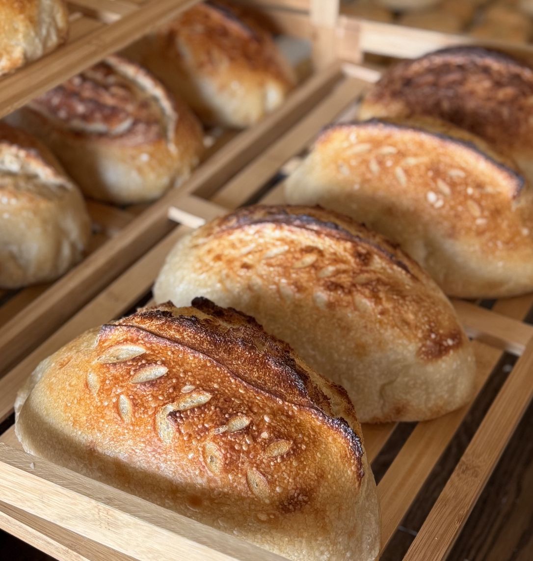 Freshly baked artisan loaves cooling on wooden racks